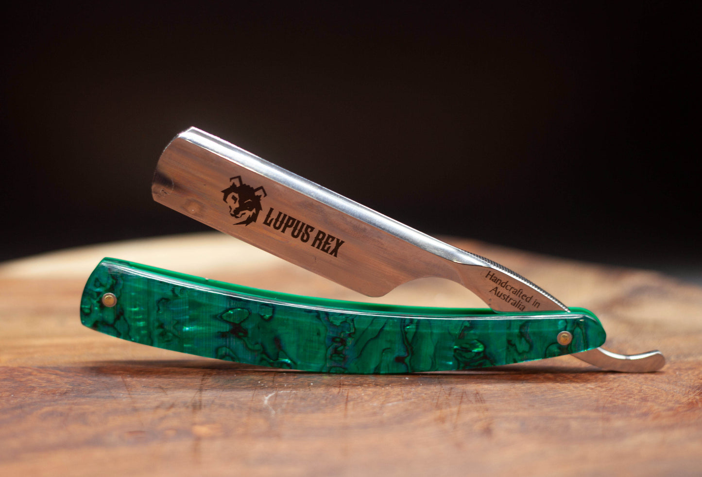 Australian handcrafted straight razor with green abalone shell scales. Lupus Rex and wolf head etched onto the blade with Handcrafted in Australia on the tang