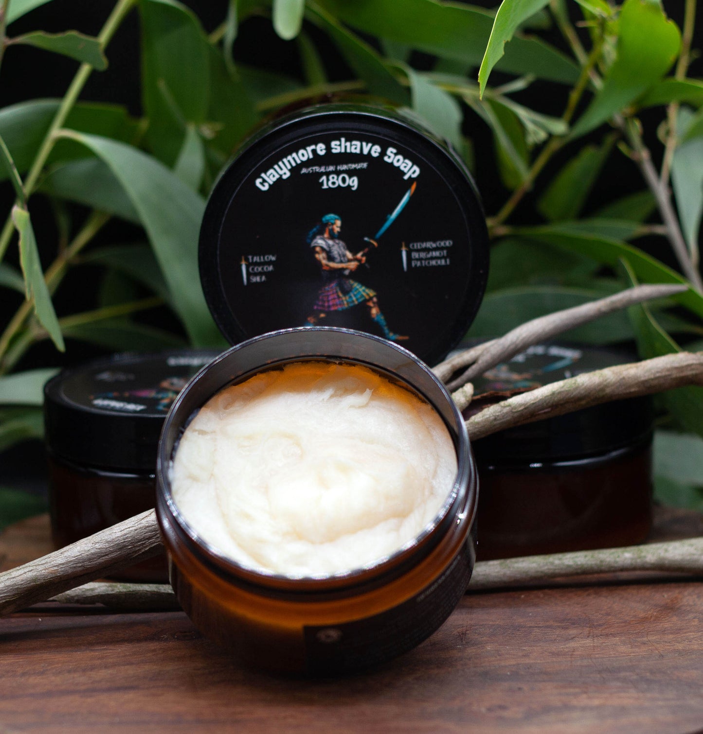 Claymore shave soap in a amber plastic container with a black lid. Tallow based and cocoa and she butters with essential oils of Cedarwood, Patchouli and Bergamot