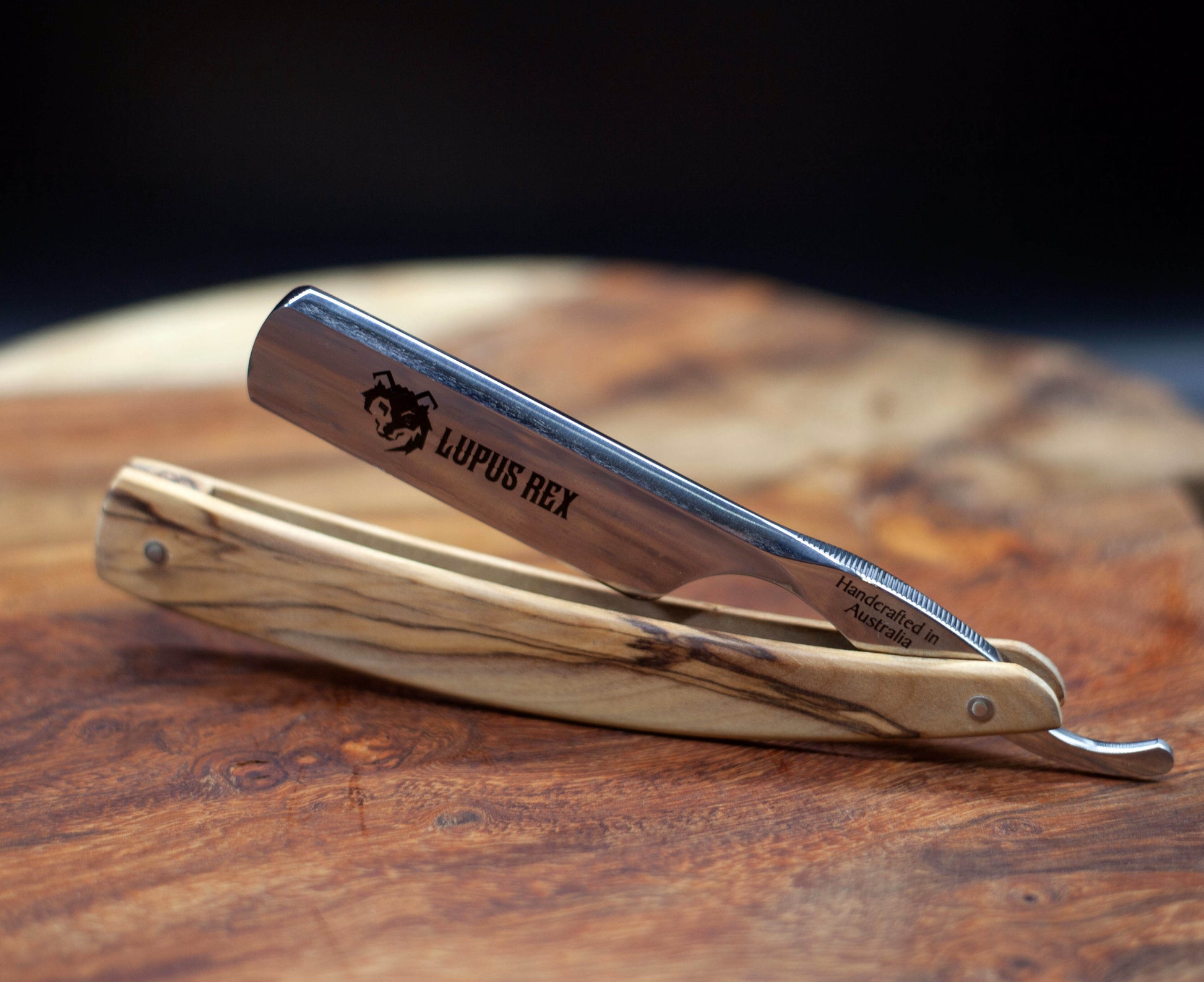 Australian handcrafted straight razor with olive wood timber scales. Lupus Rex and wolf head etched onto the blade with Handcrafted in Australia on the tang